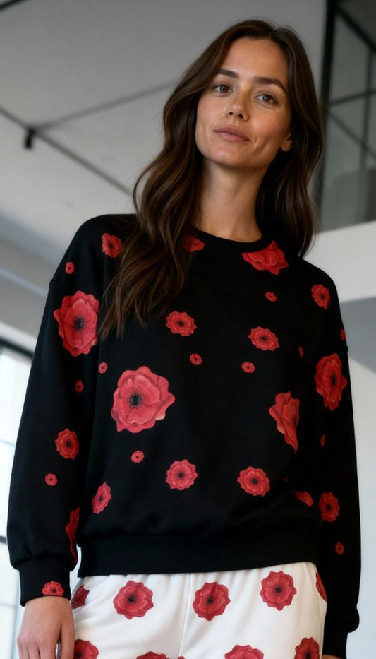 Model wearing black knitted sweater and white pants with poppy flower print
