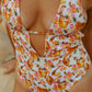 One-piece swimsuit with honeycomb and bee pattern on a beach.